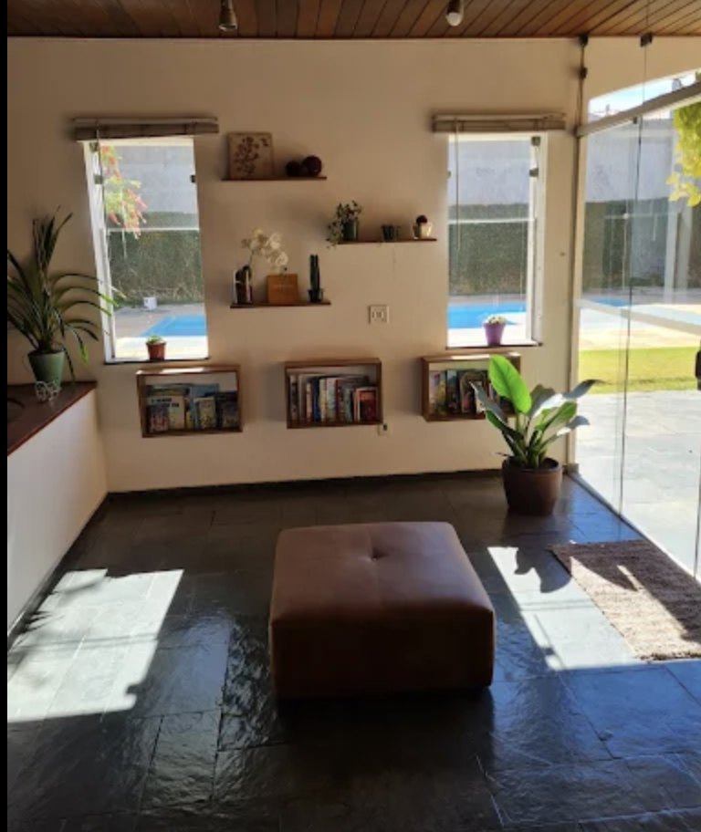 Ambiente de recepção com nichos de livros, plantas e vista para a área externa